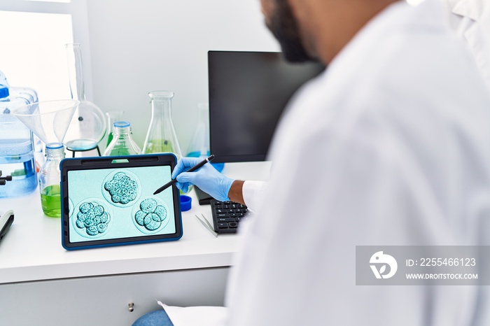 Man and woman scientist partners looking embryo image on touchpad at laboratory