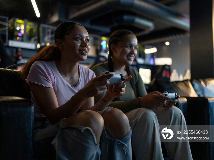 Female friends playing video games in gaming club