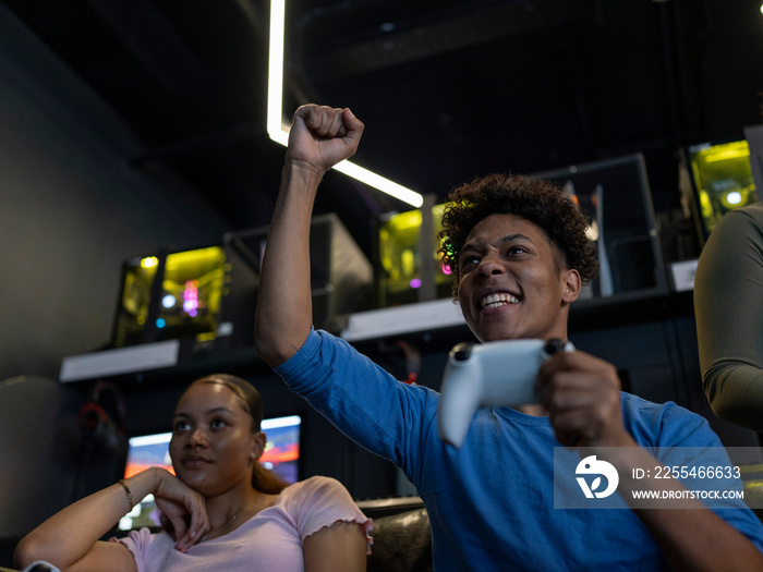 Excited man playing video games with friend in gaming club