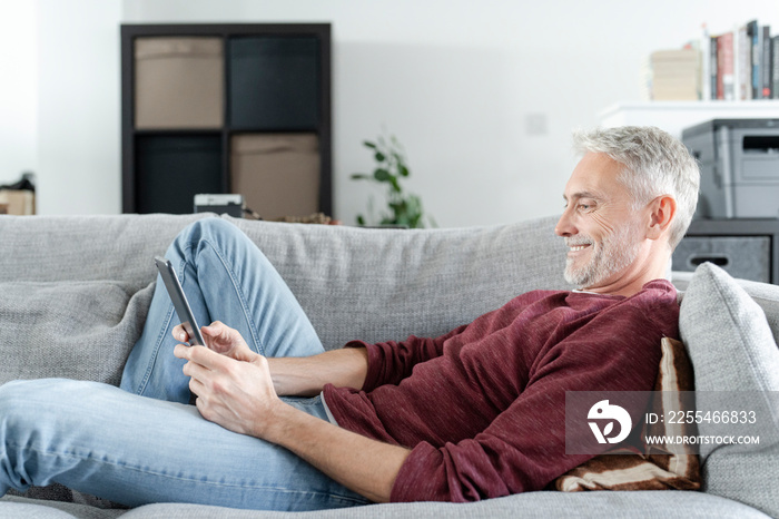 Smiling mature man using digital tablet on sofa