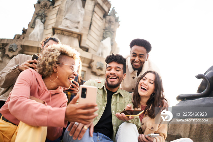 Group of students of multiple ethnicities surprised by something they are seeing on the cell phone. Teenagers using a smart phone, surfing the web.