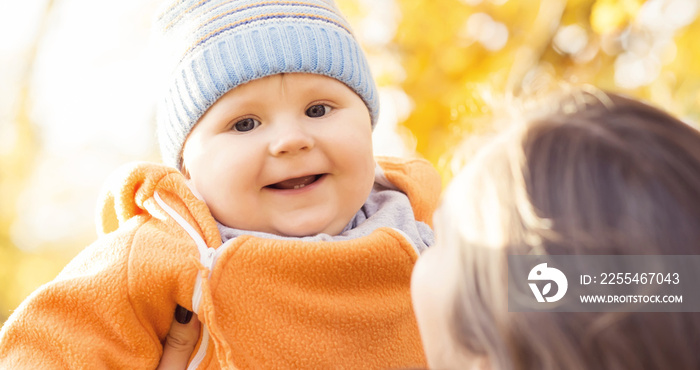 Mother playing in park with her toddler baby. Mom and son over seasonal autumn background.