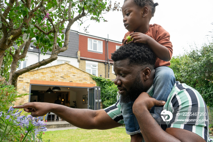 Father giving daughter (2-3) piggyback ride in garden