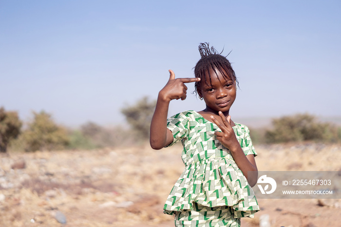 Little and cute African girl posing for the camera with hand gestures