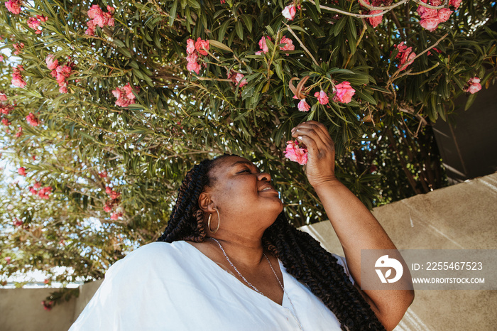 plus size African American woman smelling and looking at pink flowers