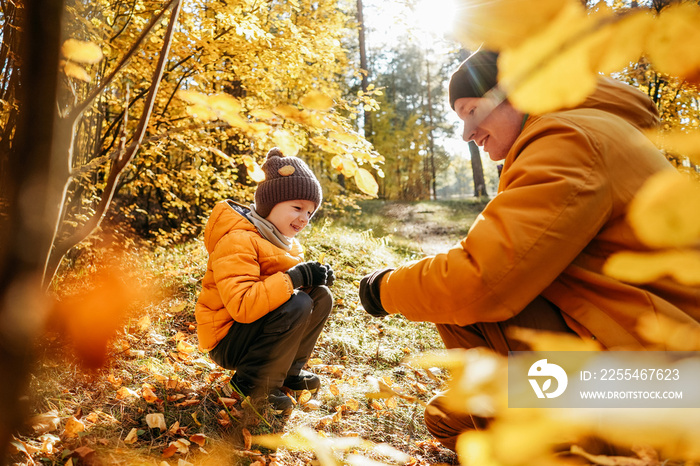 Father and son having fun in autumn forest.