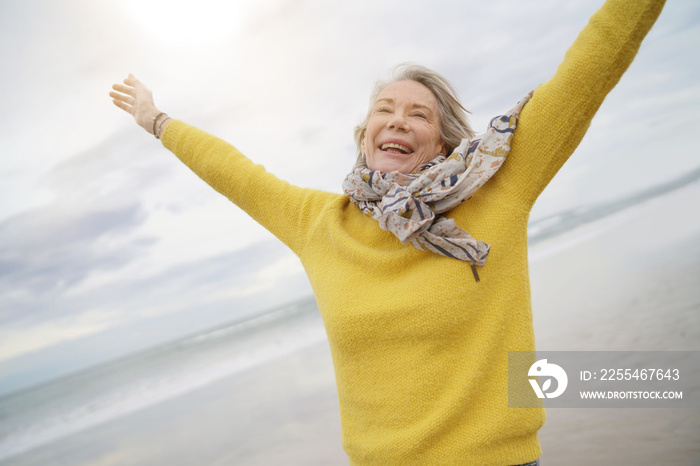 Carefree energetic senior woman playing around on beach in fall