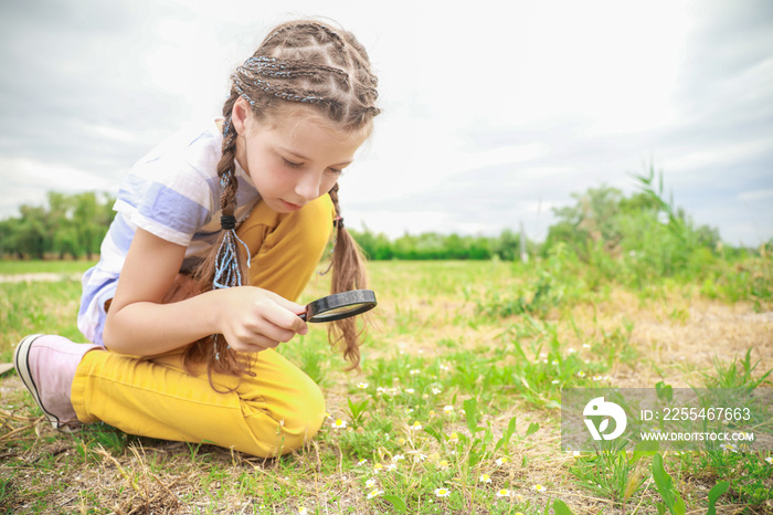 Little girl with magnifying glass studying nature outdoors