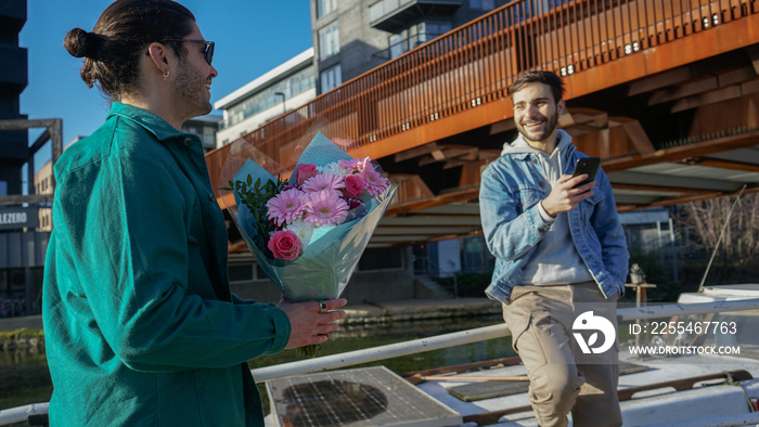 Smiling gay couple with bouquet outdoors