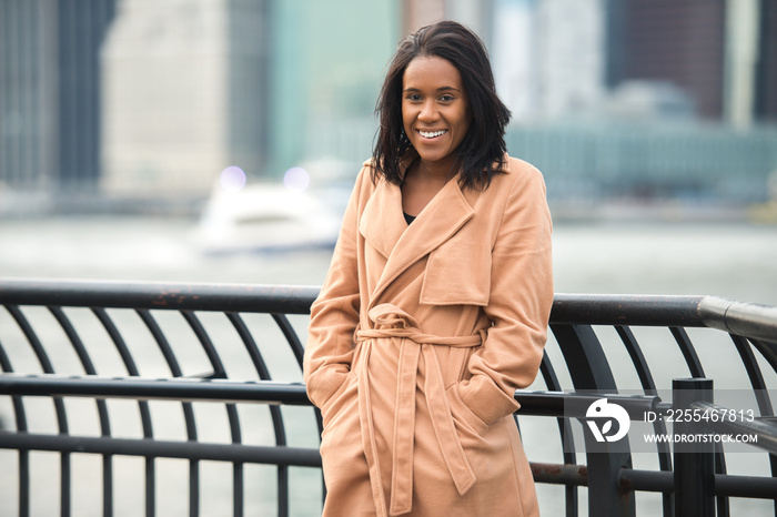 Beautiful african american woman smiling and looking in camera wearing cashmere jacket in the cold winter city