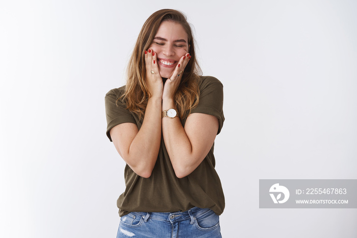 Happy good-looking positive sincere young european woman chestnut hair olive t-shirt squeez cheeks joyfilly close eyes smiling broadly white teeth grin, standing amused excited white background