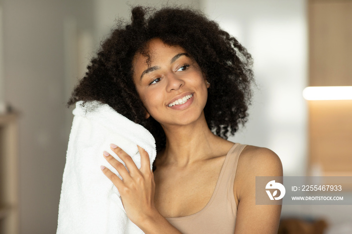 Smiling african american woman drying wet hair with towel after shower