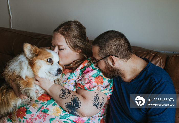 couple sits on couch snuggle dog