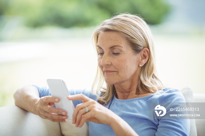 Senior woman using mobile phone in living room