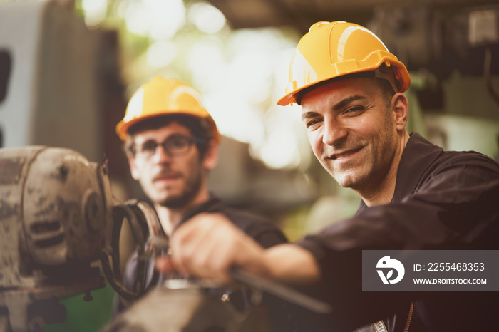 Scene of industrial workers wearing jumpsuit and yellow safety hat turn his face to camera and smile feeling like happy in the factory atmosphere, Concept life with insurance is sustainable working.