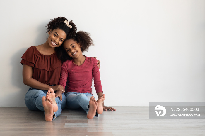 Adorable african american mother and daugher sitting on floor together