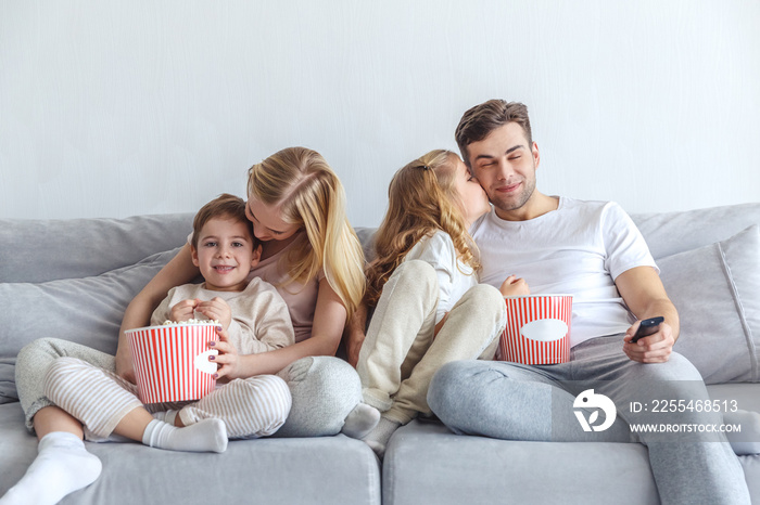 loving family watching movie on couch at home with popcorn