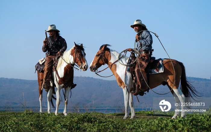 Double Western cowboy On horseback in the Mexican grassland.