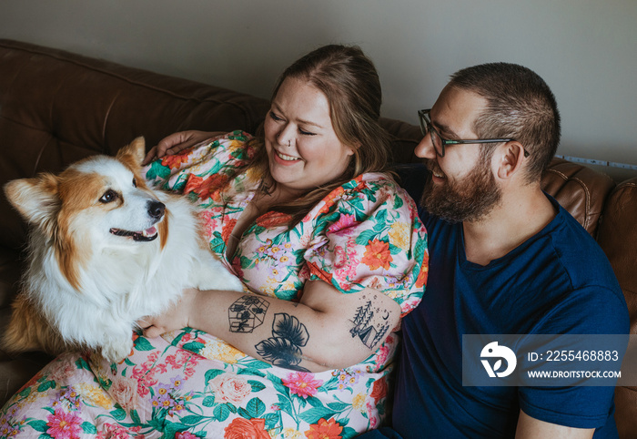 couple sits on couch with dog