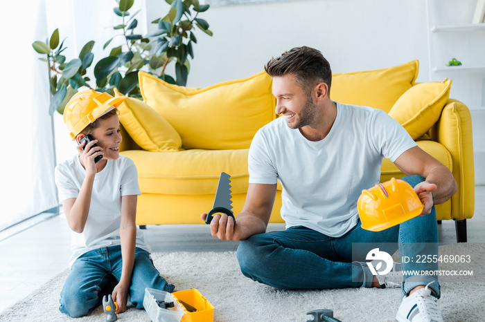 happy father looking at son playing with walkie talkie