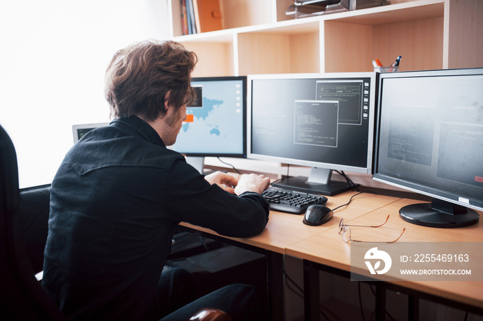 The young dangerous hacker breaks down government services by downloading sensitive data and activating viruses. A man uses a laptop computer with many monitors