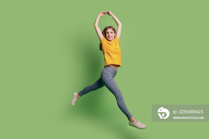 Portrait of cute charming ballerina lady jump dance wear yellow t-shirt jeans footwear on green background