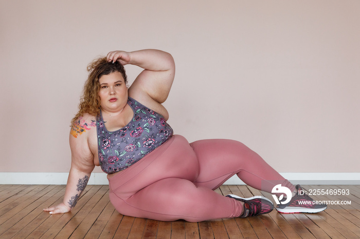 plus size woman sitting on the floor wearing workout gear