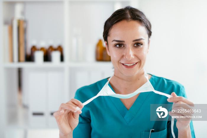 Young female doctor in medical office. Beautiful female doctor putting mask on.