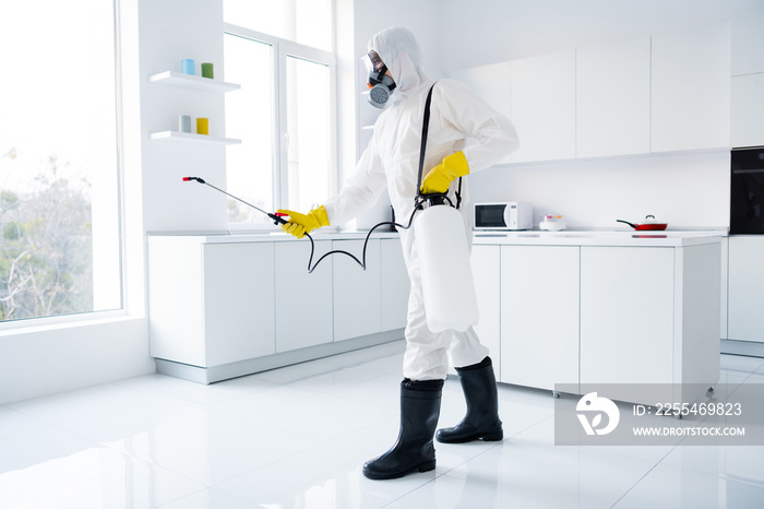 Full body profile side photo of focused guy cleaner in coverall spray sprayer window kitchen whitre surface prevent covid contamination epidemic spreading indoors house