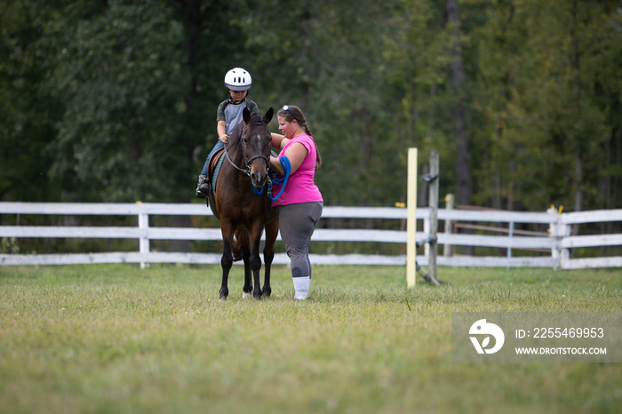 Young boy on a pony with an instructor