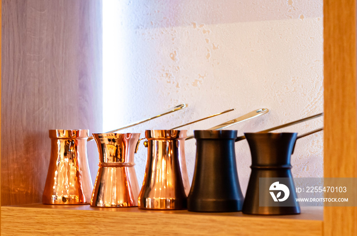 soft focus of traditional turkish copper cezve and ibrik for sale on wooden shelf in coffe shop