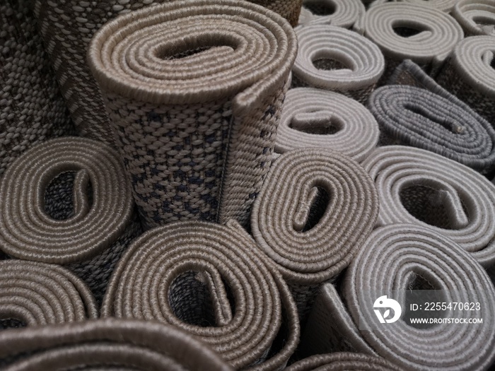 Carpets rolled up in stock. Gray spiral pattern carpets on display in a store.