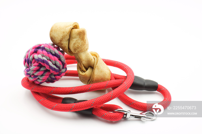 Red dog leash with a ball of string and a meat bone on a white background