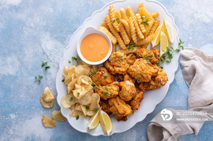 Fish and chips on a serving platter with dipping sauce