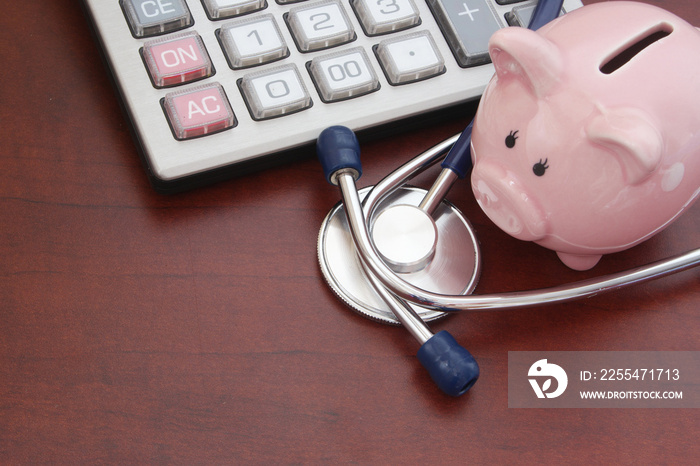 Cost of medical examination concept, piggybank, calculator and stethoscope on table