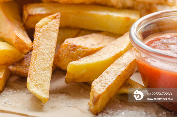 Traditional British street food fish and chips with ketchup sauce on parchment paper