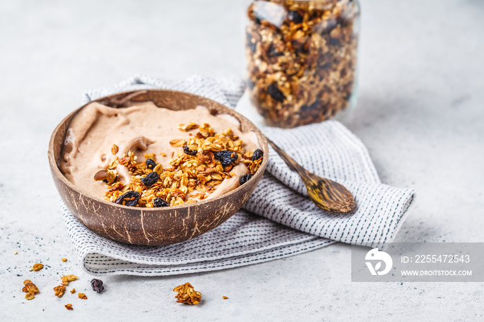 Chocolate smoothie bowl with granola in a coconut bowl, copy space.