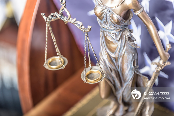 Bronze figurine of Themis holds wedding rings on scales of balance, being in foreground. Couple divorce.