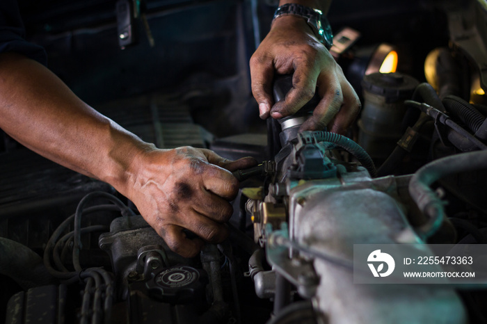 Repairman Working with dirty hands and tools fixing car engine at service shop.