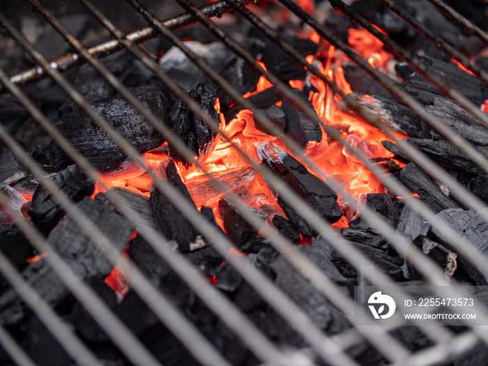 View through the grid of a barbecue. Close-up of glowing charcoal and embers.