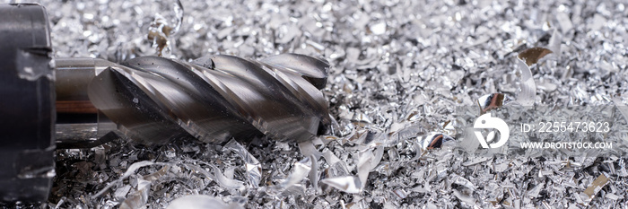 Panoramic image. Silver end mill cutter with metal shavings. Processing of ferrous metals in a factory