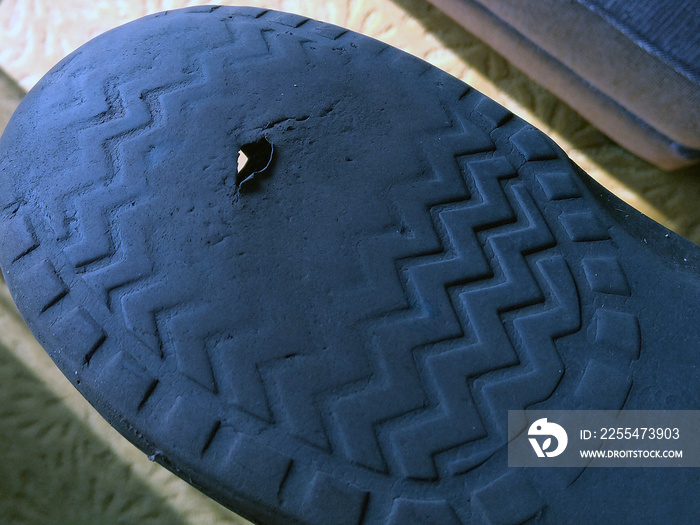 Worn out sandal with hole in sole.