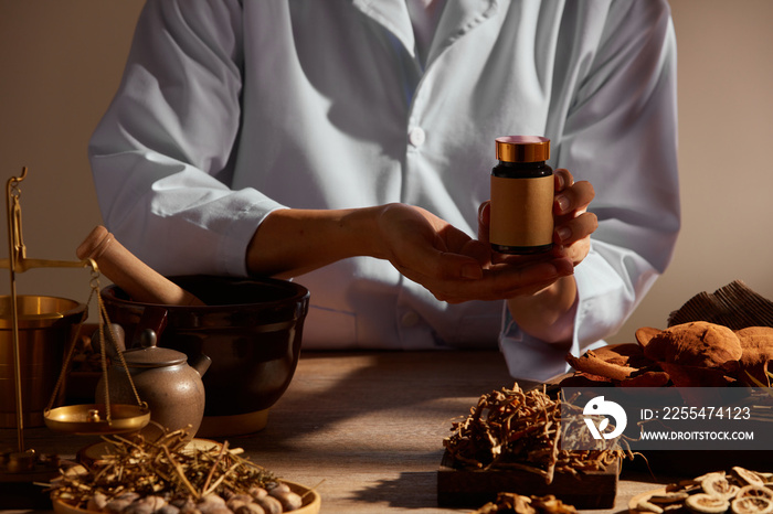 Traditional chinese medicine with herb and spices in brown wooden background mortar and pestile  , doctor holding a medicine jar for advertising ,  traditional content