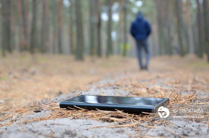 Young man loses his smartphone on Russian autumn fir wood path. Carelessness and losing expensive mobile device concept