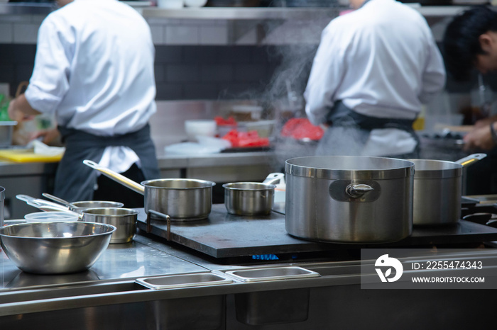 professinal kitchen staff working behind steam pot in the kitchen