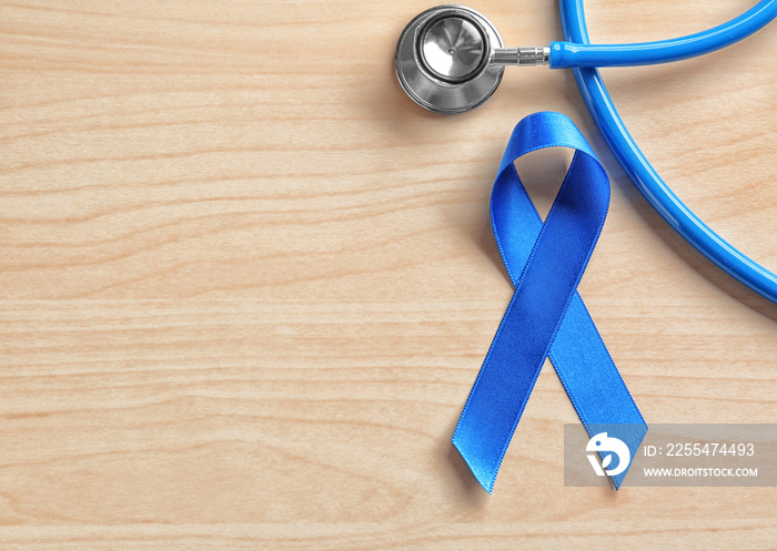 Blue ribbon and stethoscope on wooden background. Cancer awareness concept