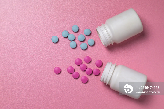 Blue and pink pills spill out of white jars