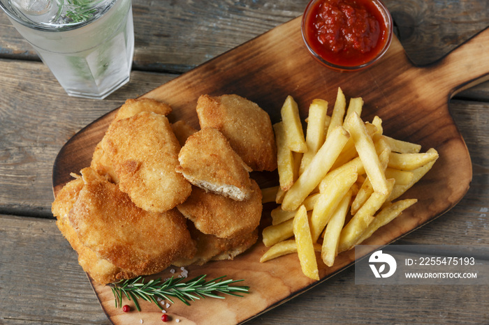 chicken nuggets french fries on the board with red sauce