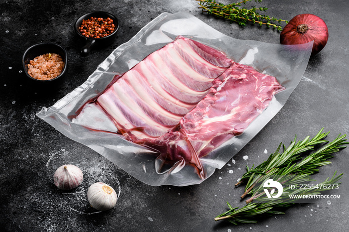 Supermarket packaged raw lamb rib rack, on black dark stone table background