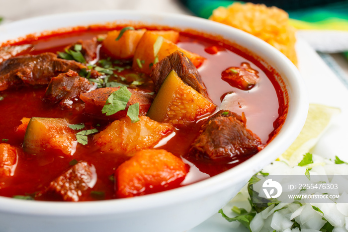 A view of a bowl of red beef soup, also known as caldo de res.